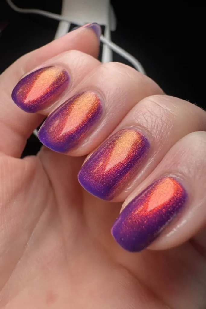 August Nails Ideas showcasing a shimmering magnetic cat-eye effect in vibrant orange and purple tones