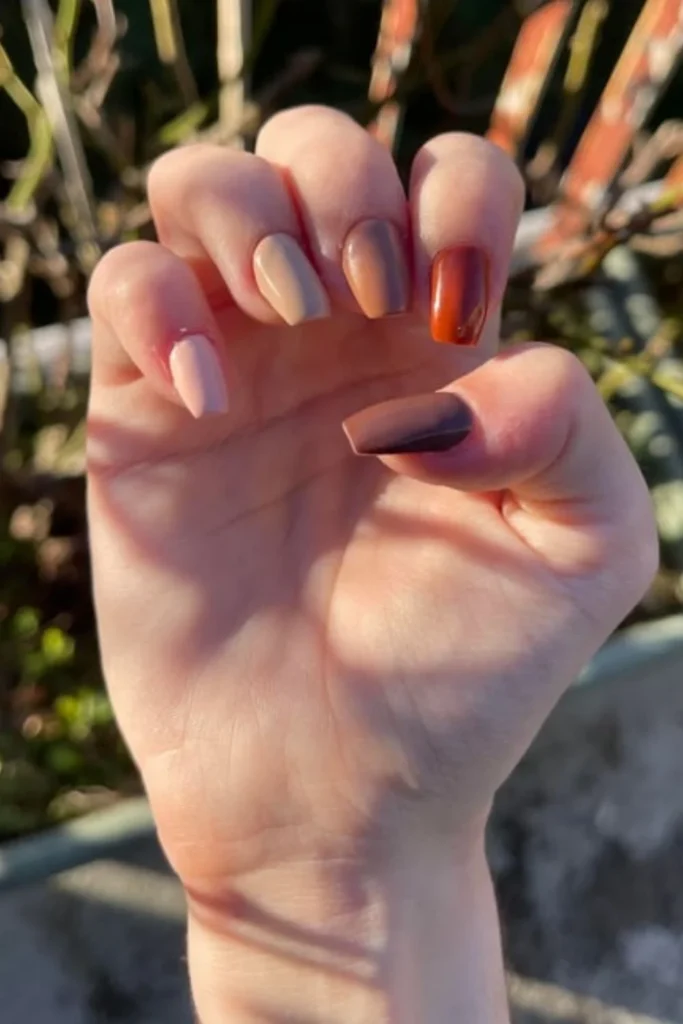 Gradient skittle manicure ranging from nude and mocha to rich terracotta and dark chocolate brown for fall transition nails ideas