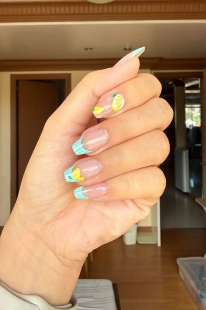 Light blue French tip nails with hand-painted yellow lemons for end of summer nails