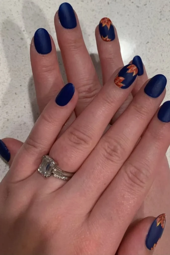 Matte navy blue nails featuring warm autumn leaf art accents for fall transition nails ideas