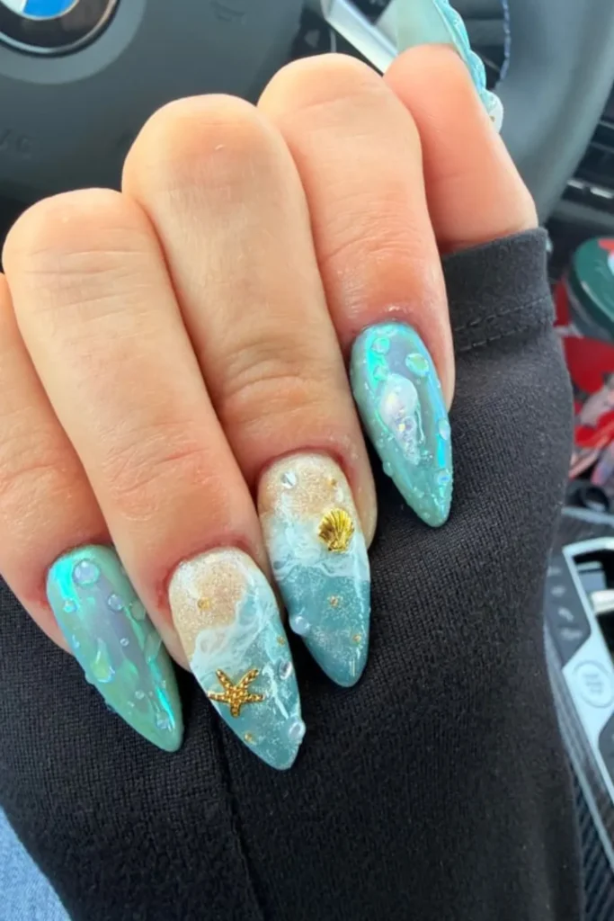 Ocean wave nail design with sandy beach gradient, water droplets, and gold starfish charms for vacation nails ideas