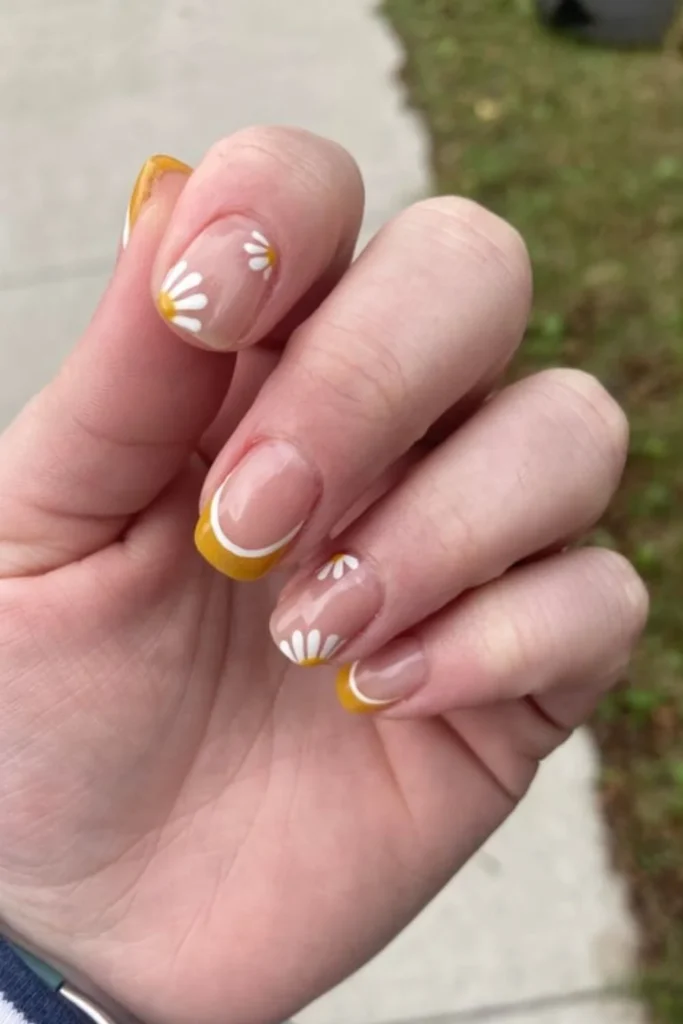 Short natural nails with mustard yellow French tips and delicate white side-daisy accents for fall transition nails ideas