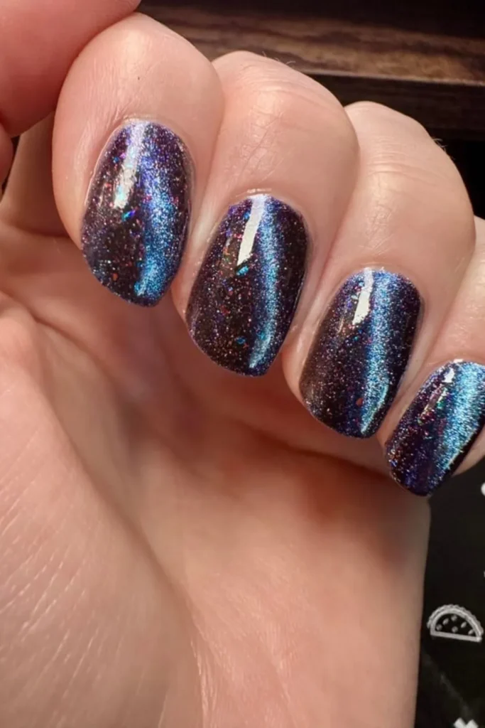 Cosmic September nails ideas featuring short rounded nails painted in a deep blue and purple magnetic cat-eye polish with subtle glitter flakes