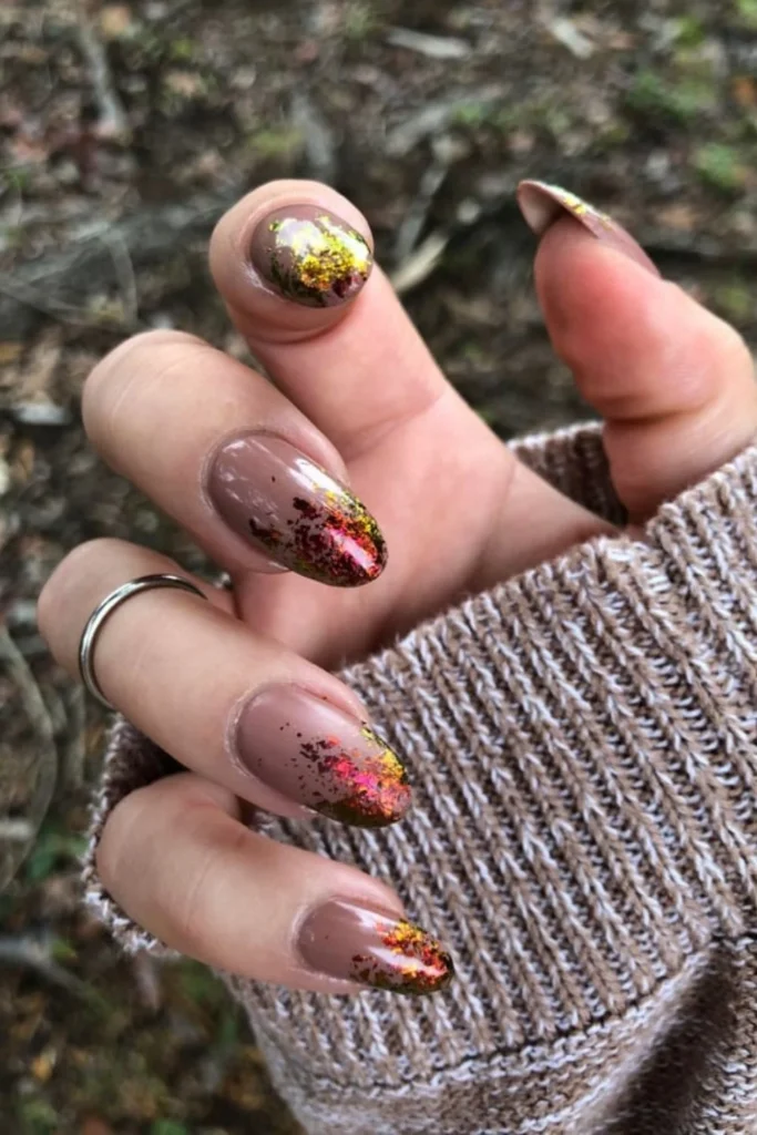 Fall foliage September nails ideas styled on almond nude nails with sparkling copper and red metallic foil flakes concentrated at the tips
