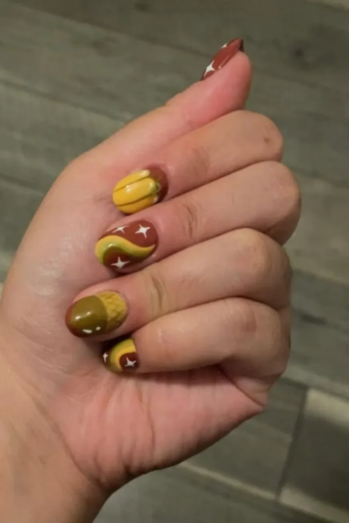 Fall harvest September nails ideas featuring short round nails styled with pumpkin, acorn, and retro swirl hand-painted nail art in earth tones