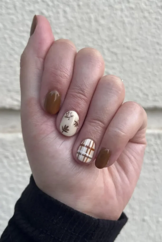 Minimalist September nails ideas featuring short rounded nails painted in warm chocolate brown, paired with accent nails featuring delicate metallic bronze autumn leaf art and a simple brown plaid pattern on a nude base